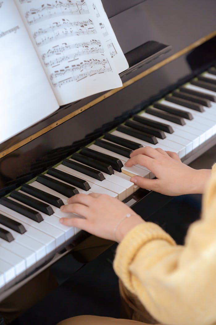 Prestations Close-up of a woman playing piano with sheet music, capturing musical talent and concentration.